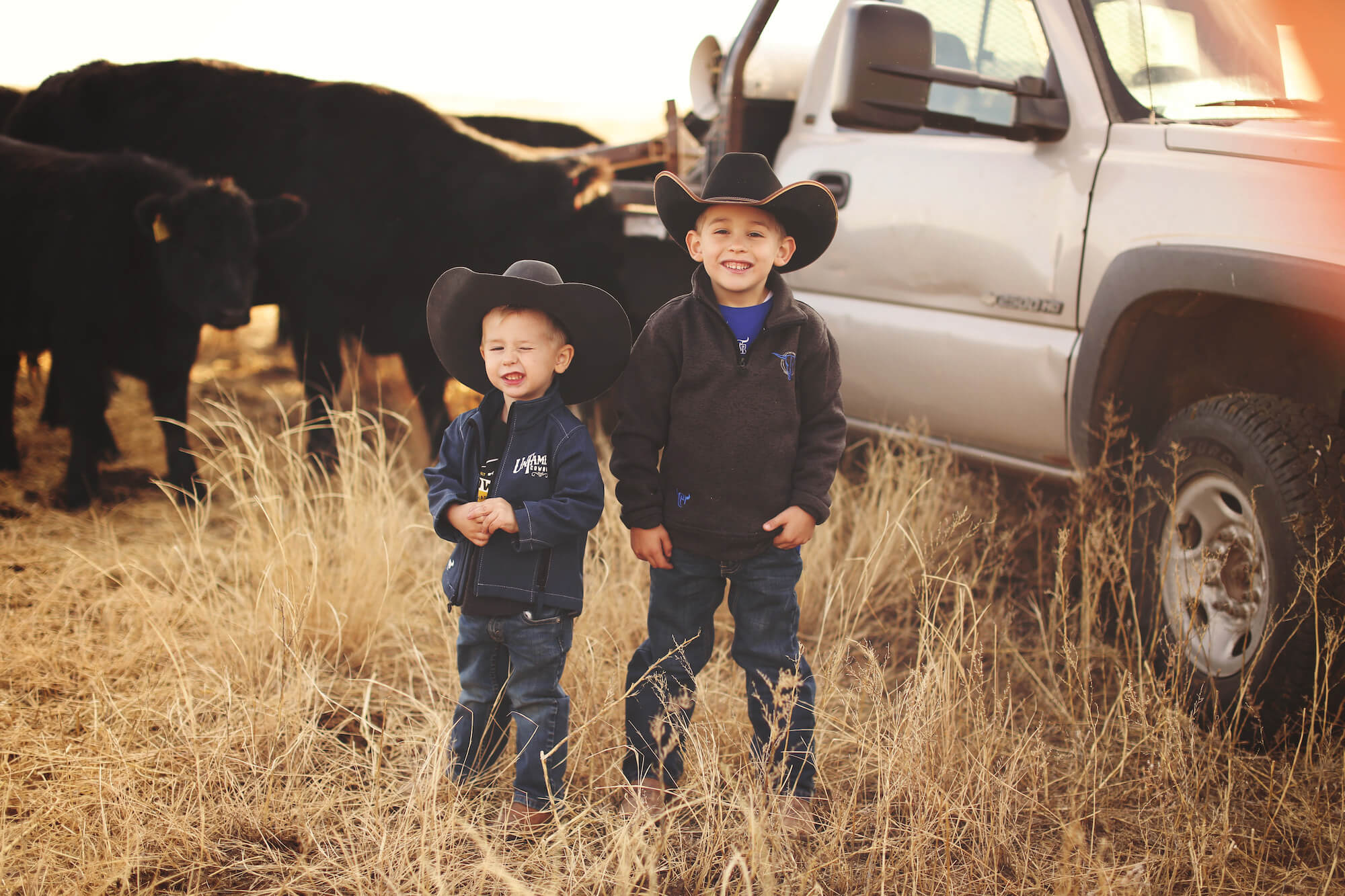 Two boys wearing western wear by truck