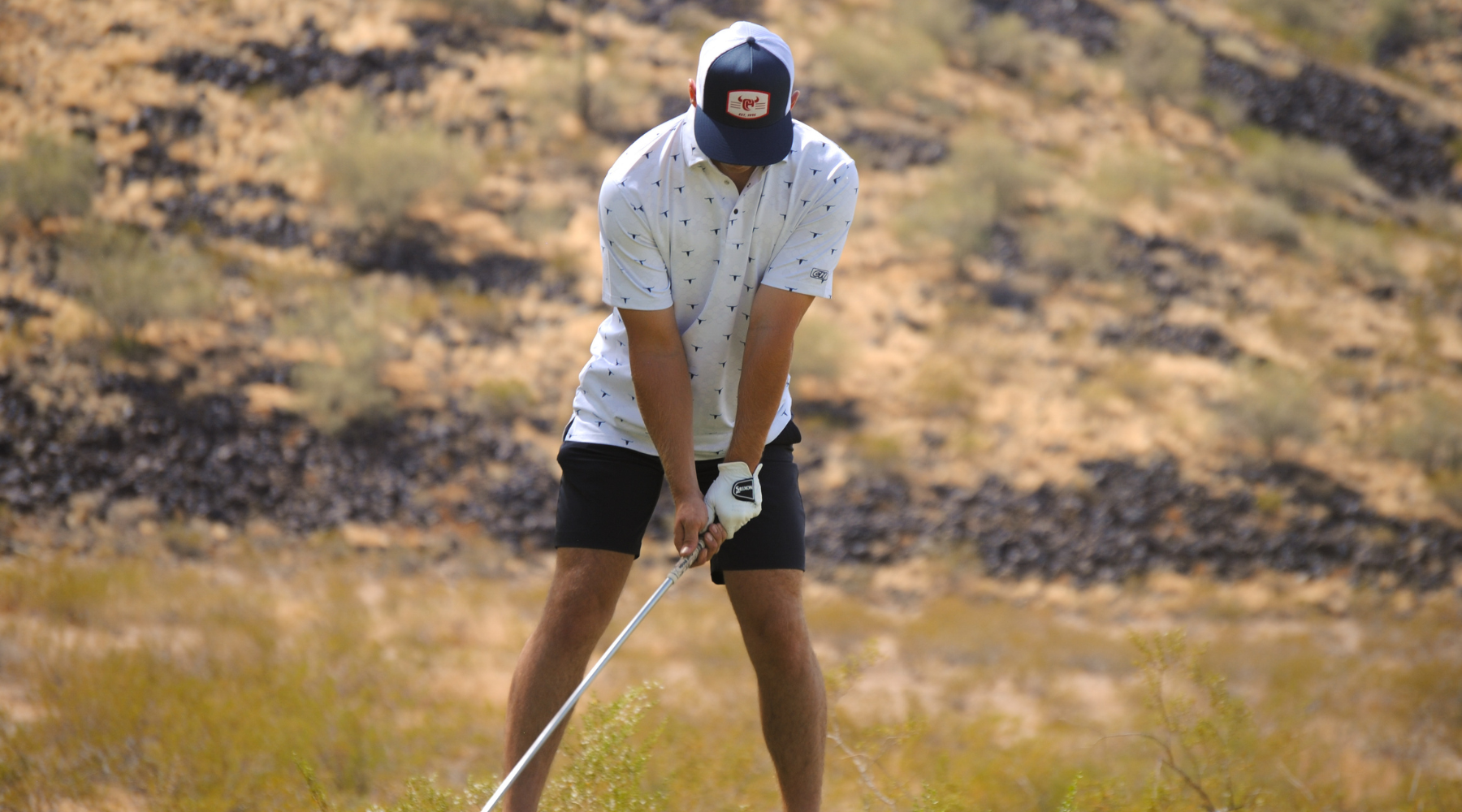 Cowboy golfing while wearing a men's western polo.