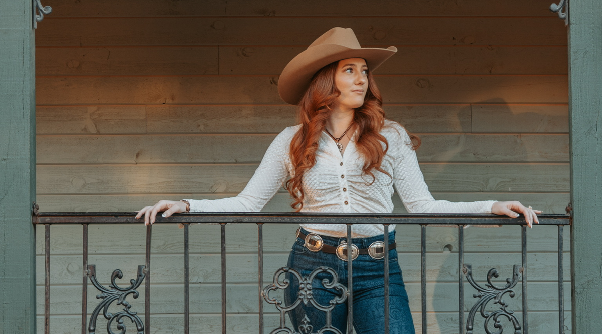 Cowgirl looking out over her ranch while wearing women's Cowboy Hardware apparel.
