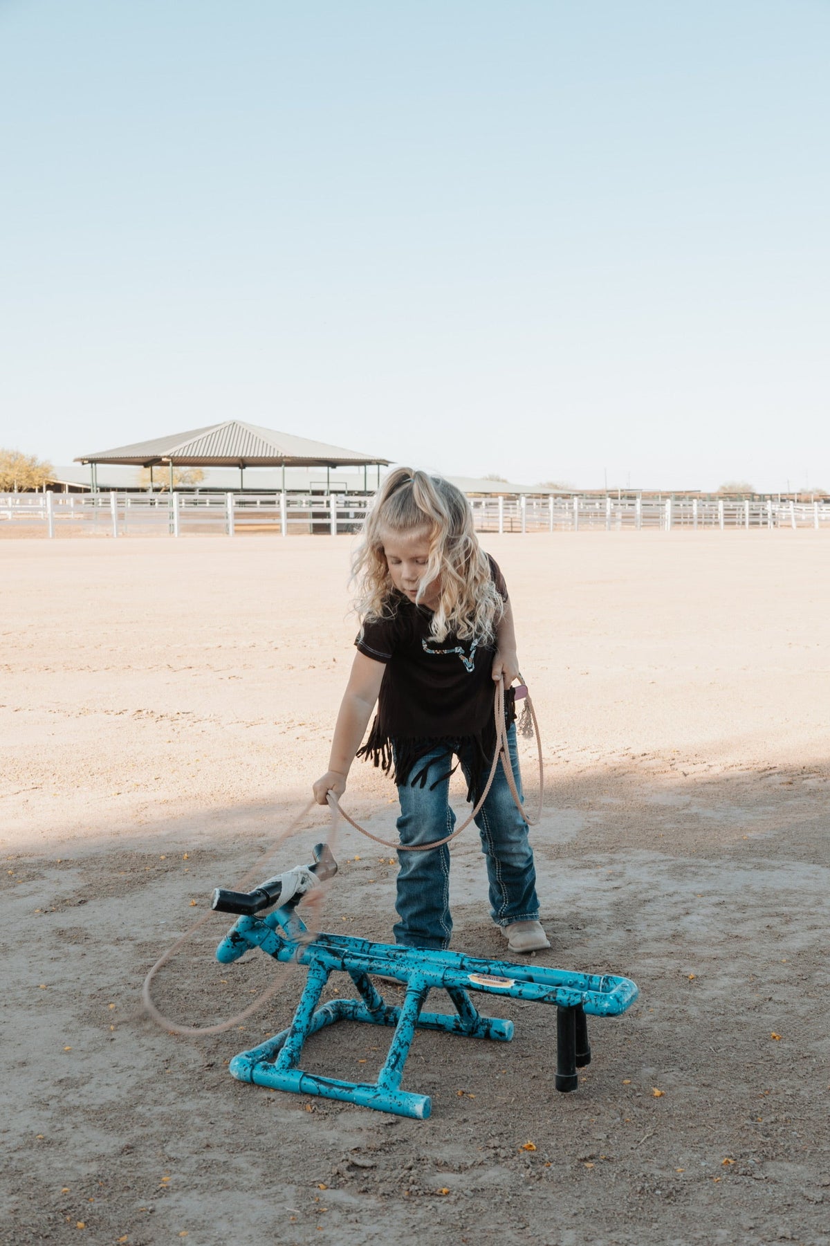 Little cowgirl practicing her roping while wearing a Cowboy Hardware infant and toddler girls top.