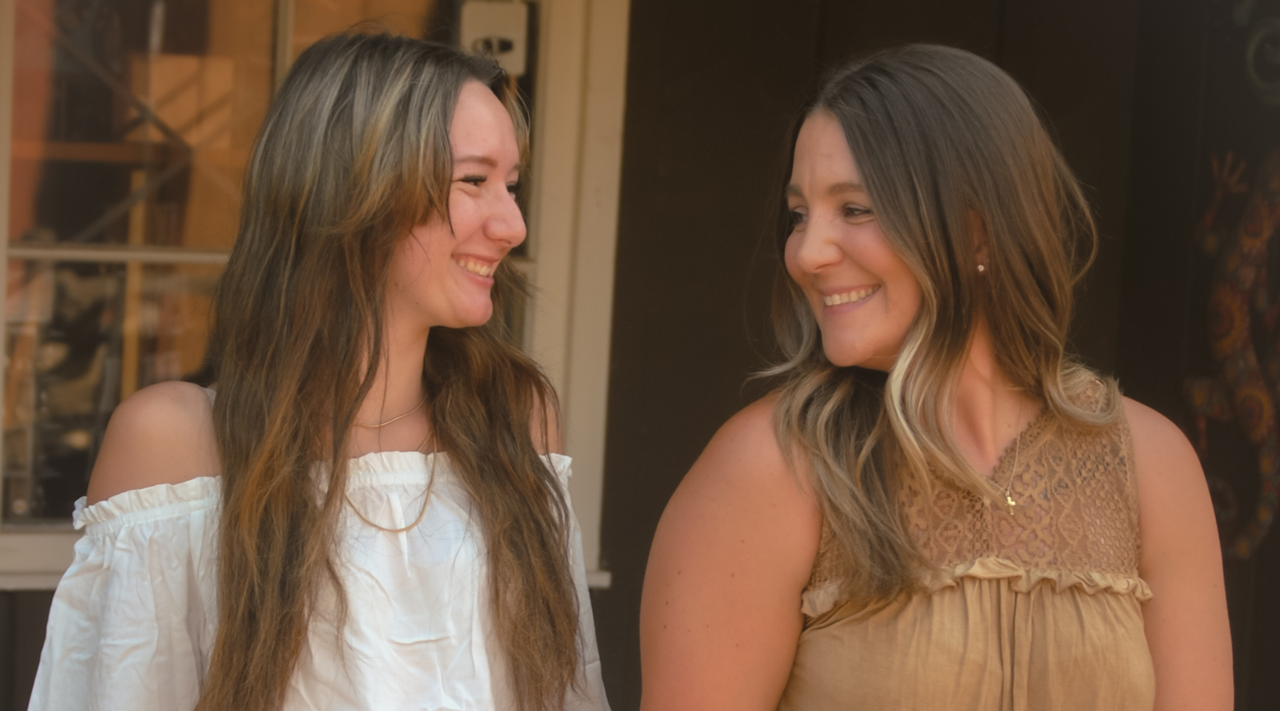 Two cowgirls socializing while wearing Cowboy Hardware women's tops.
