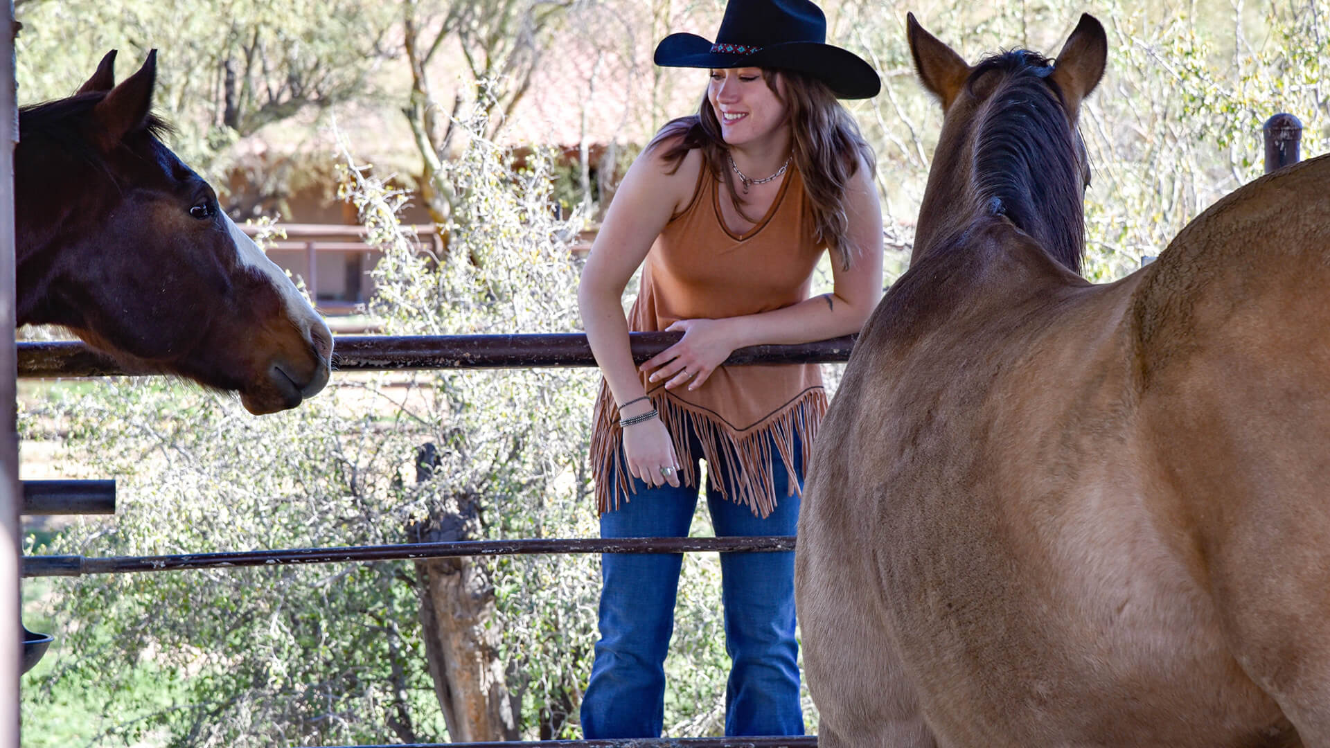 Cowgirl looking at horse in a women's western wear outfit from Cowgirl Hardware