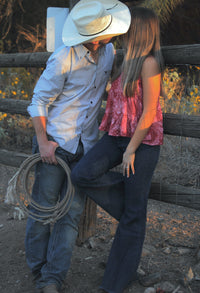 Cowgirl kissing cowboy out in the corral.