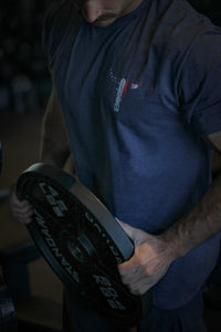 Man lifting weights wearing Cowboy Hardware heather navy "Freedom Is Never Free" shirt