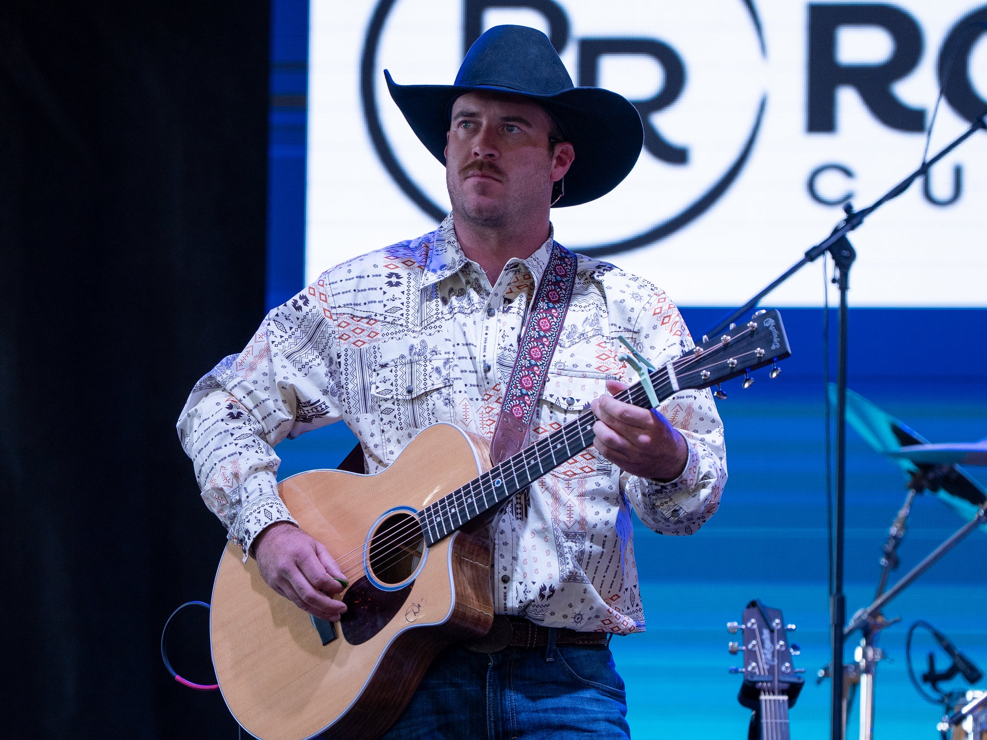Man playing guitar on stage with a blue background and 'PBR' logo.