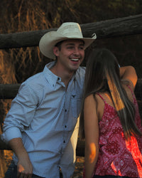 Cowboy laughing talking to cowgirl leaning on fence wearing Cowboy Hardware's white puzzle star long sleeve western shirt