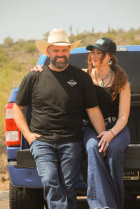 Cowboy and Cowgirl sitting on the bed of a truck in an outdoor setting