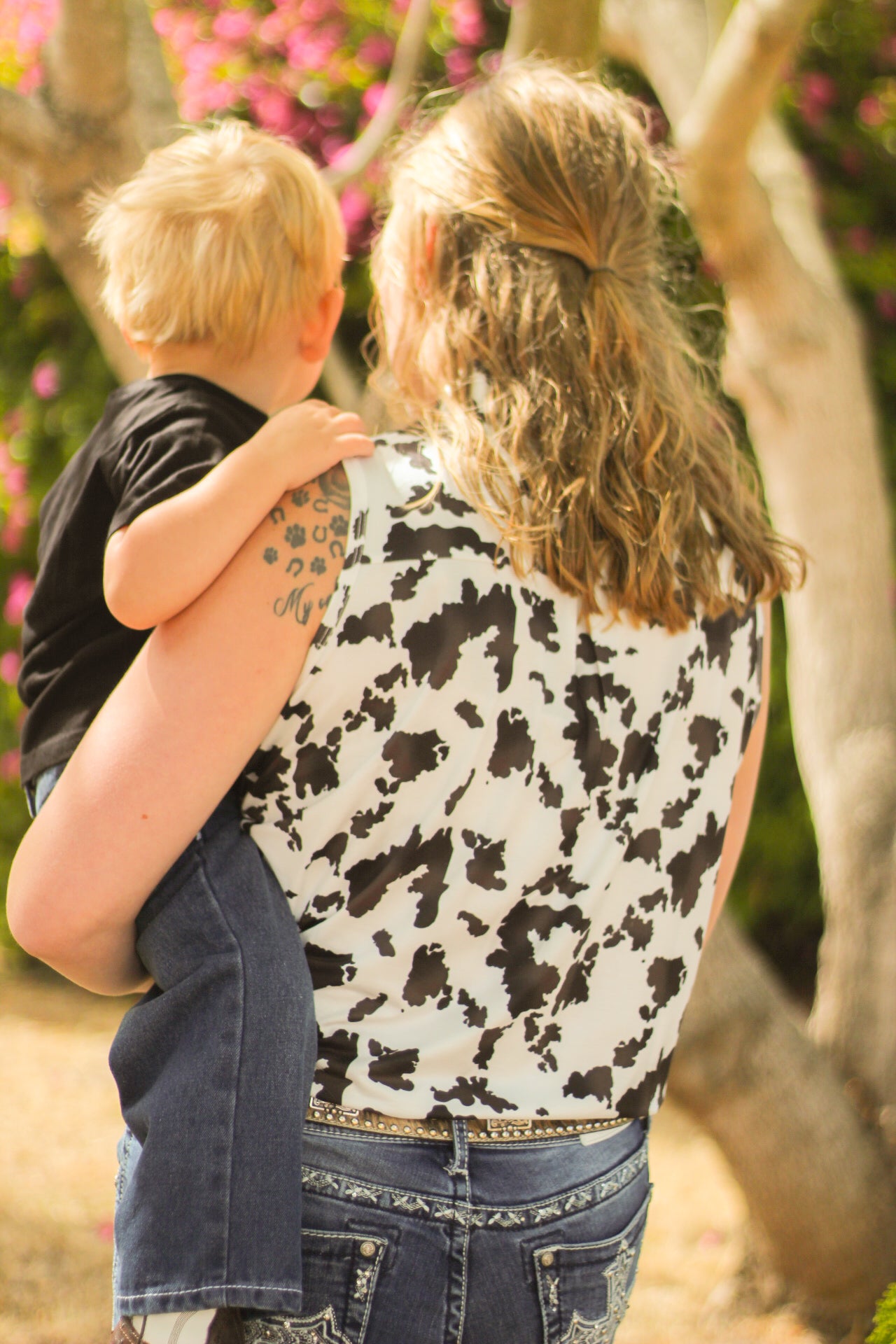 Woman with a child in a park, wearing a cow print shirt.