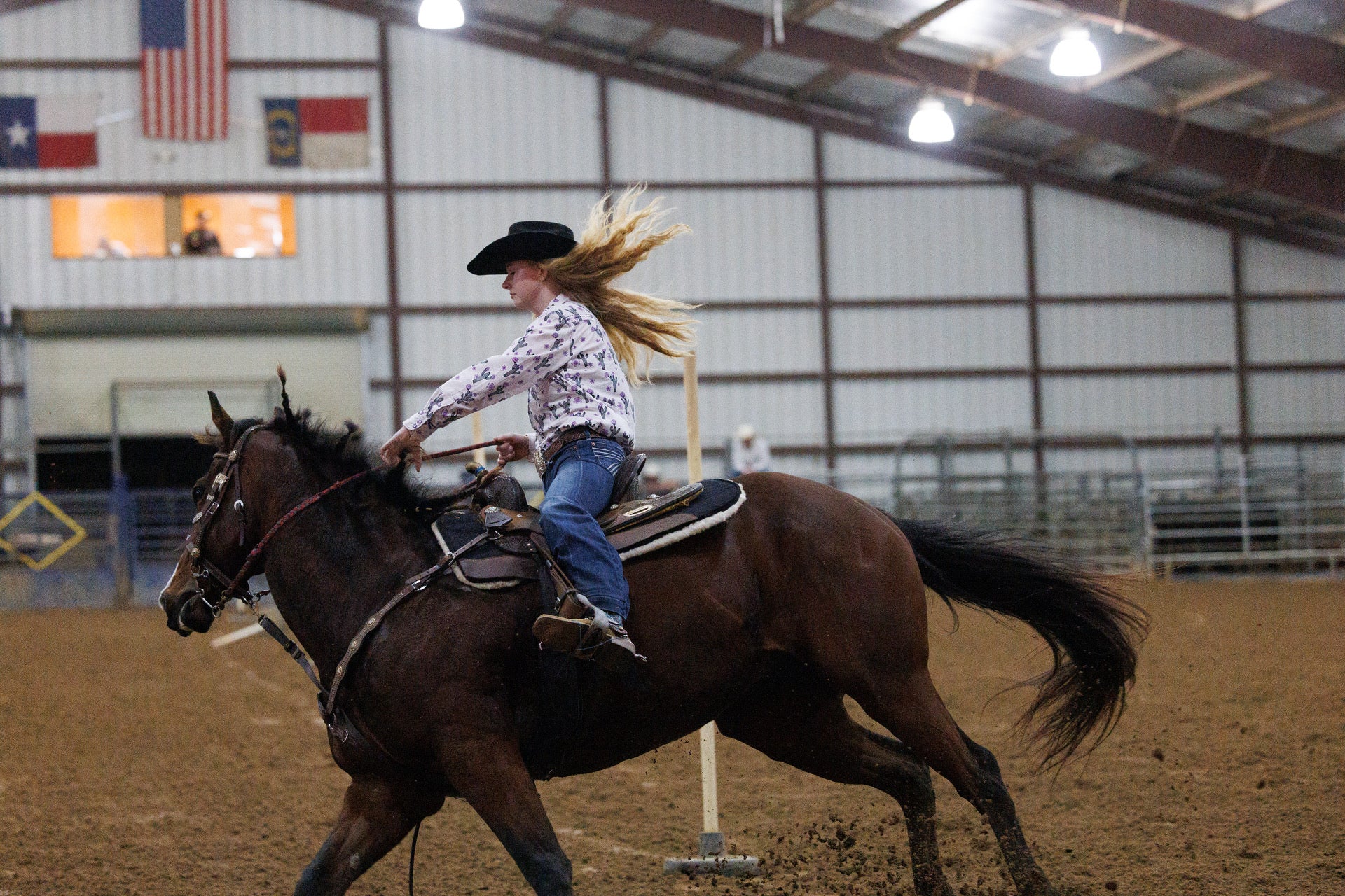 Cowgirl making a quick turn around a barrel on her horse.