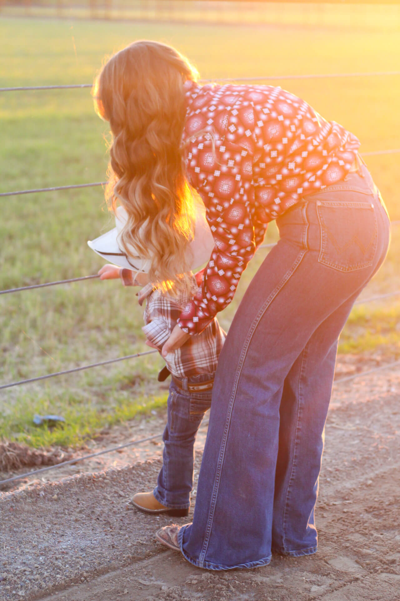 Cowgirl with her son looking at cows.