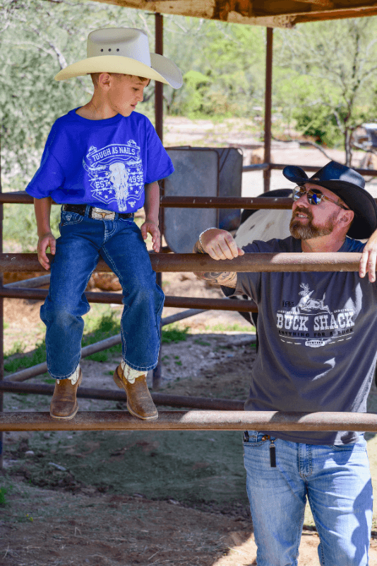 Little cowboy learning how to rope some cattle wearing Youth Boy's Royal Blue Tough as Nails Short Sleeve T-Shirt Cowboy Hardware.