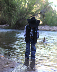Little Cowboy standing in creek wearing Cowboy Hardware's tonal aztec accent black poly shell vest