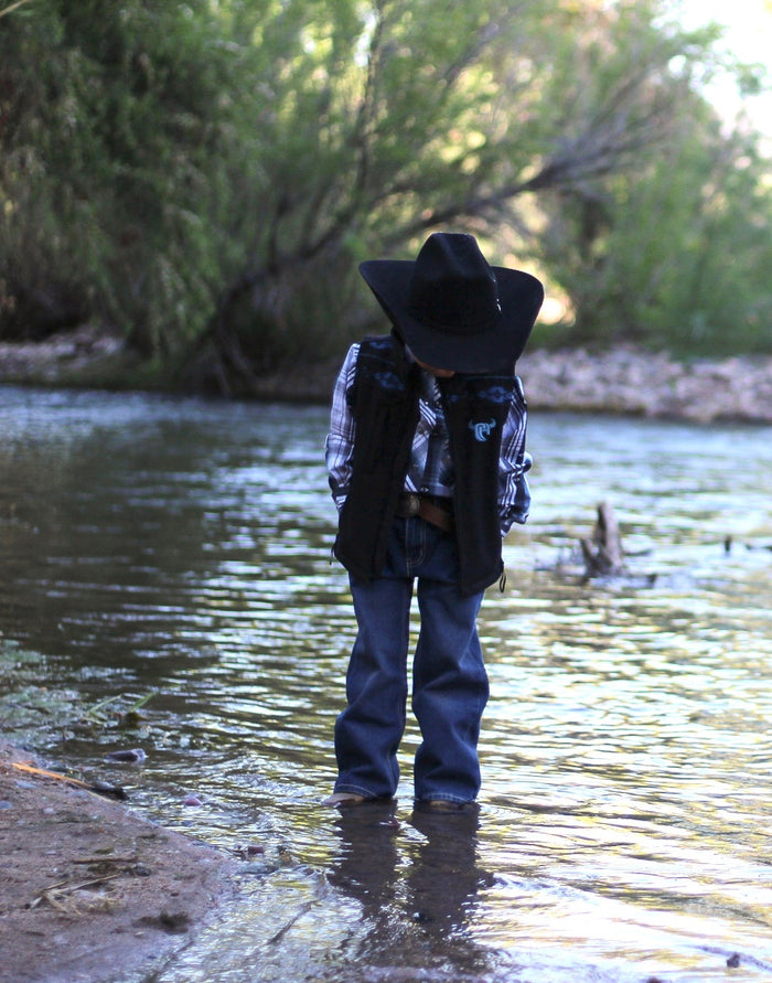 Little Cowboy standing in creek wearing Cowboy Hardware's tonal aztec accent black poly shell vest