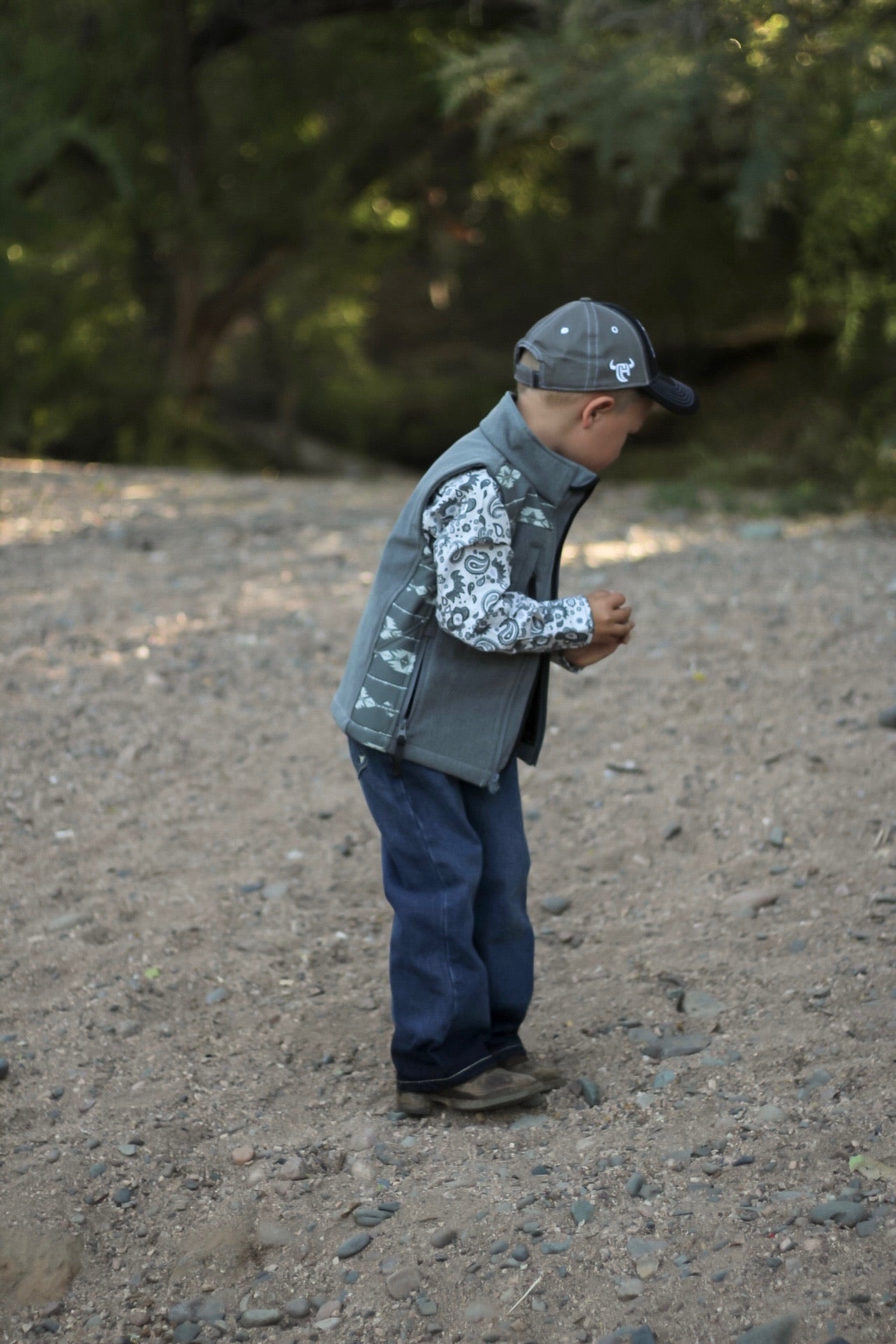 Little cowboy standing in woods wearing western outfit with Cowboy Hardware's boys fun aisley white long sleeve print under vest