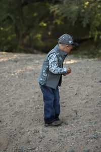 Little cowboy standing in woods wearing western outfit with Cowboy Hardware's boys fun aisley white long sleeve print under vest