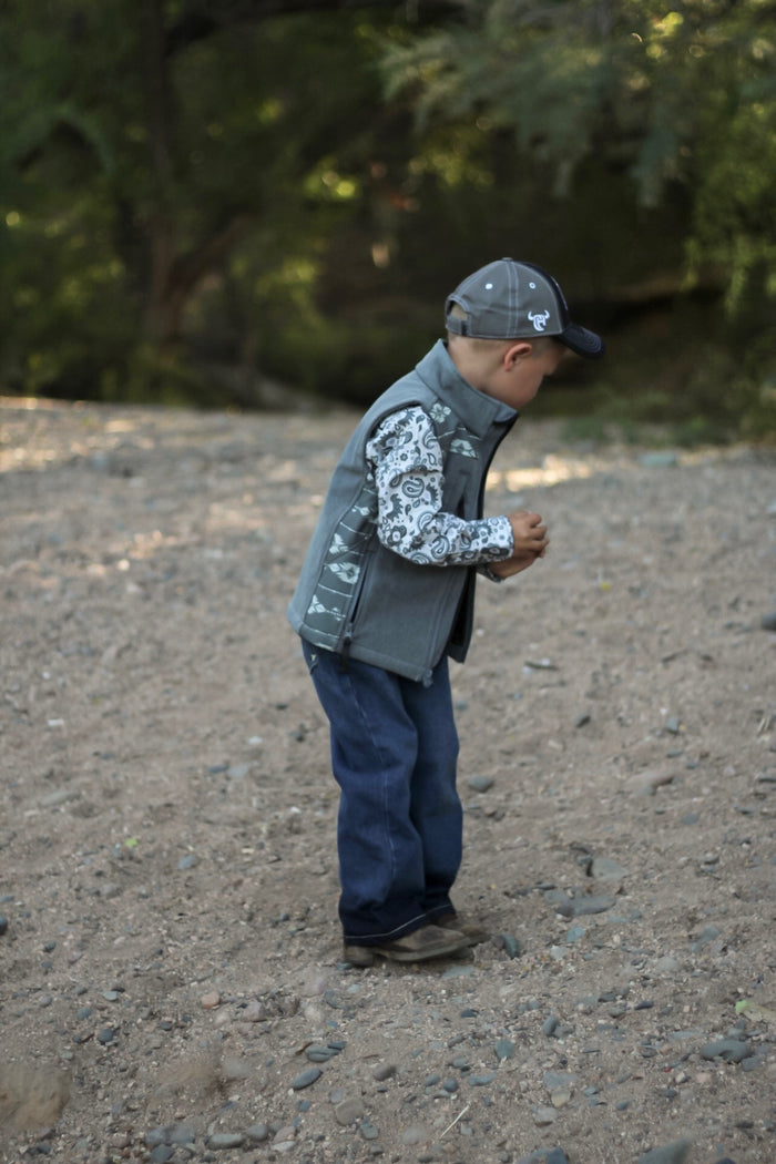 Little cowboy standing in woods wearing western outfit with Cowboy Hardware's boys fun aisley white long sleeve print under vest