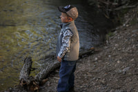 Little cowboy staring at creek wearing boy's Cowboy Hardware tonal aztec accent grey poly shell vest