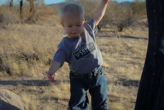 Little cowboy wearing Cowboy Hardware's CH Aztec Serape Graphite Heather Short Sleeve T-Shirt standing in the desert