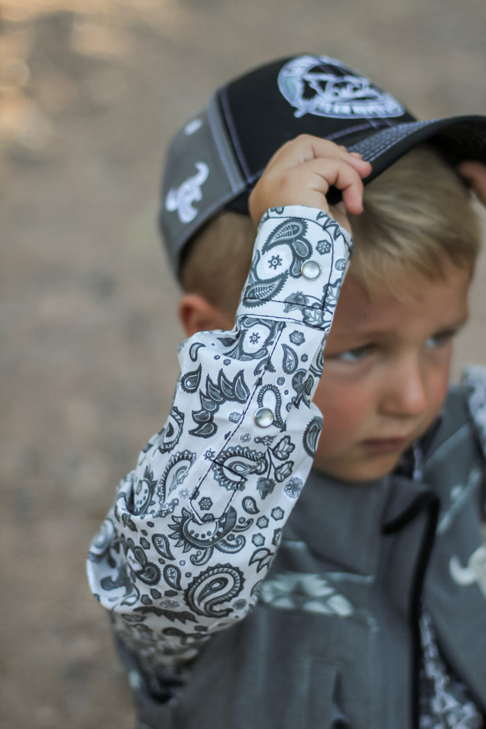 Little cowboy wearing full western outfit with Cowboy Hardware's boys fun aisley white long sleeve print under vest