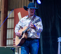 Man playing guitar on stage with a blurred background
