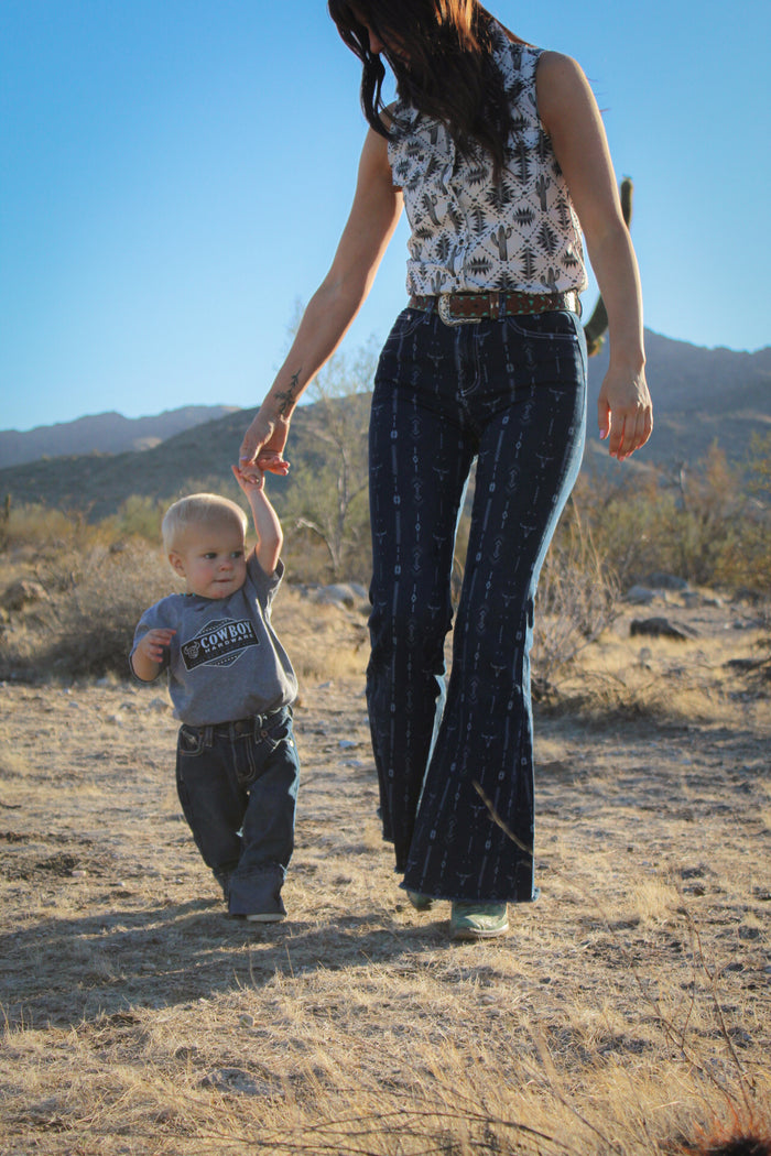Toddler cowboy holding mother's hand walking wearing Cowboy Hardware's denim triple barbed jeans