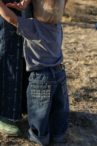 Toddler cowboy leaning on mother wearing Cowboy Hardware's denim triple barbed jeans