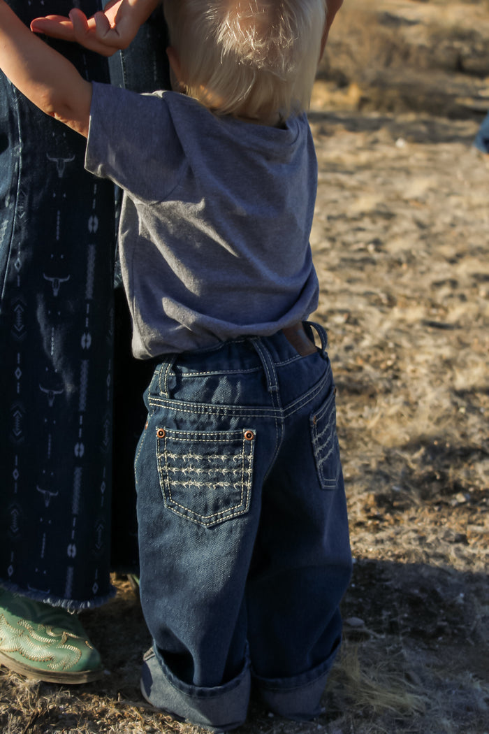 Toddler cowboy leaning on mother wearing Cowboy Hardware's denim triple barbed jeans