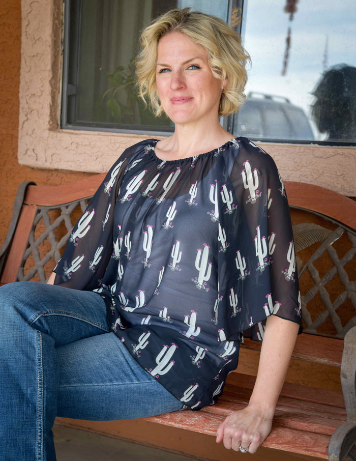 Western lady sitting on front porch bench wearing women's Cowgirl Hardware black and white all over saguaro angel 3/4 sleeve blouse