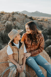 Young cowboy and his mother sitting on a rock