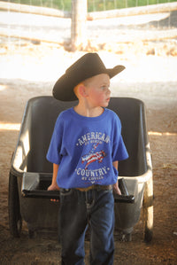 Young cowboy doing ranch chores wearing Youth Boys Cowboy Hardware Royal Blue American By Birth Short Sleeve Tee.