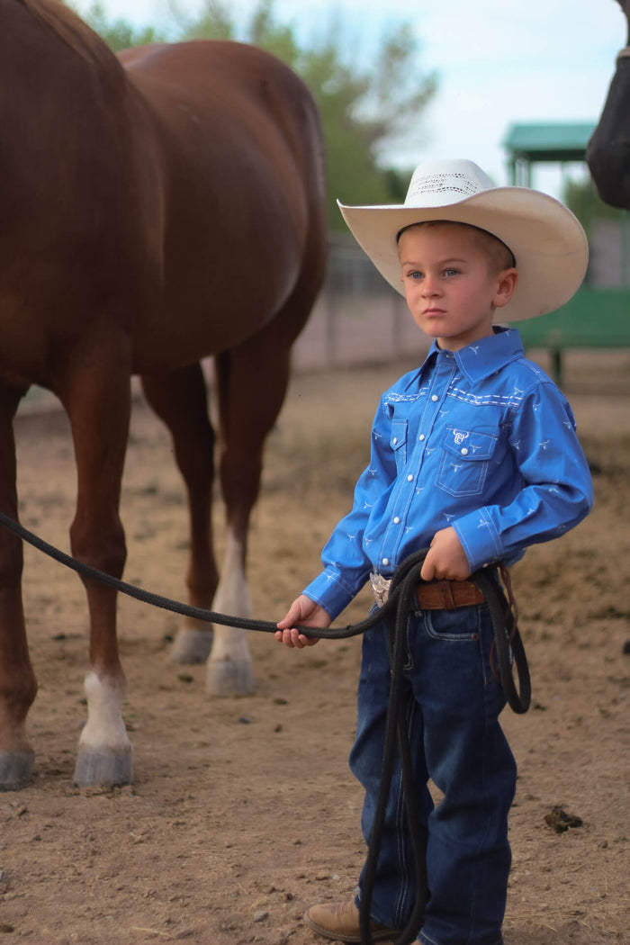 Young cowboy in the corral with his horse.