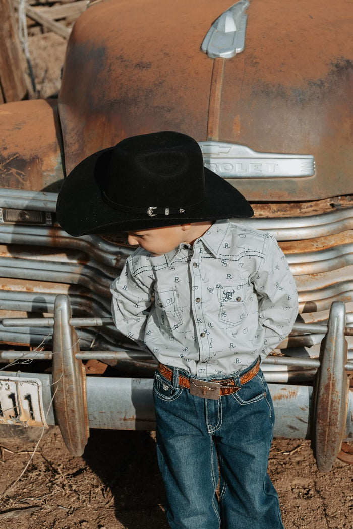 Young cowboy leaning against an old truck.