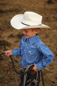 Young cowboy learning how to rope some cattle.