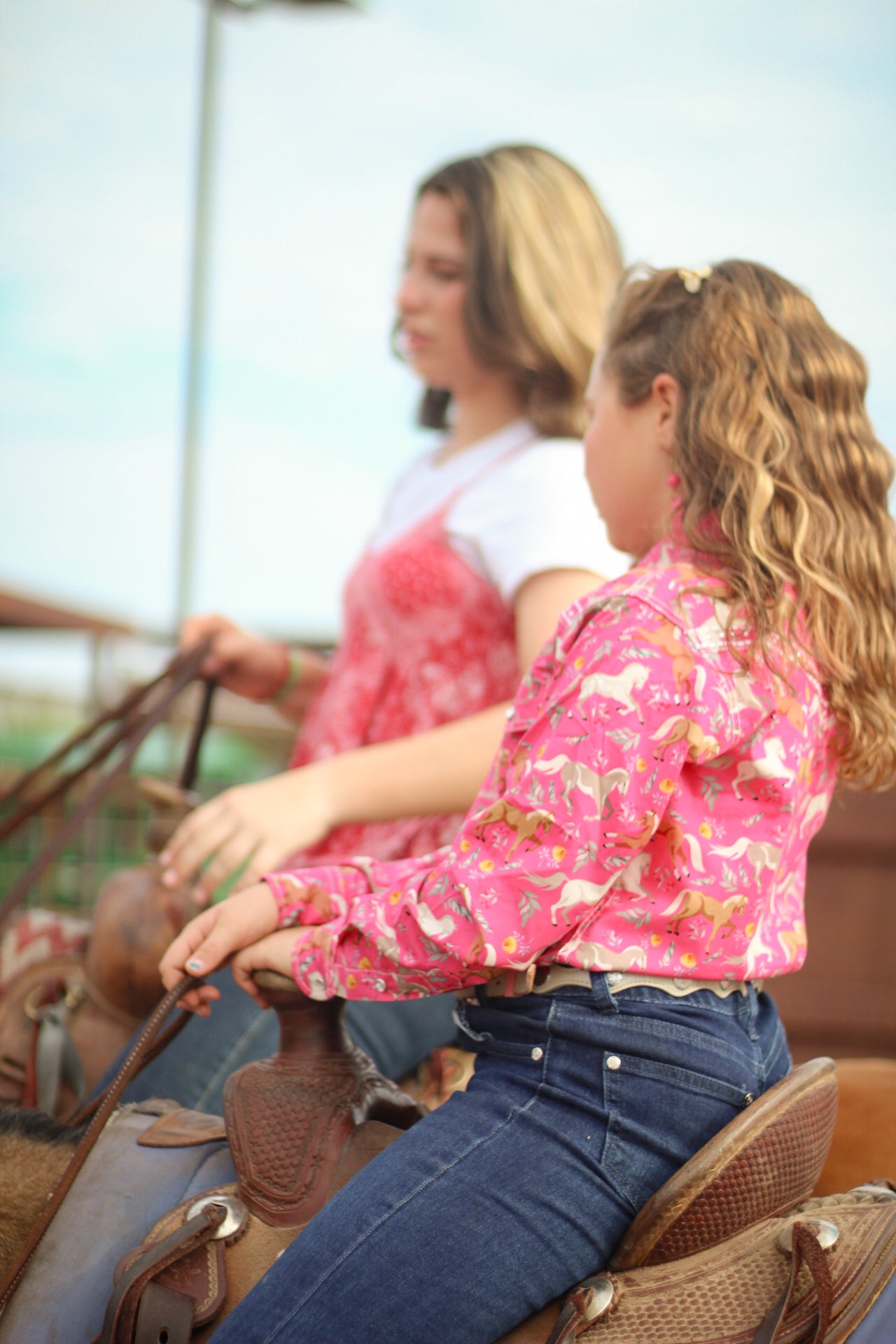 Young cowgirl riding her horse with her mother.